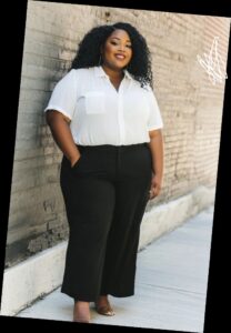 A plus size woman in a White short-sleeve button-down shirt with chest pocket

Black high-waisted wide-leg trousers

Nude/Tan strappy heeled sandals

Long silver earrings