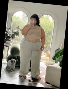 For the baddie girlies, here are some ways to eat up that baddie look 10 A plus size woman in Taupe short sleeve crewneck top Green wash wide leg jeans Pink slides Silver hoop earrings Silver ring