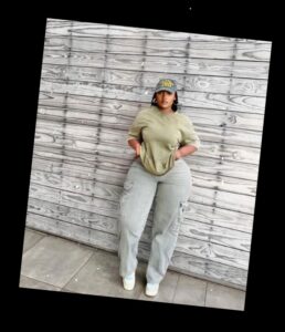 For the baddie girlies, here are some ways to eat up that baddie look 2 A plus size woman in Grey and yellow trucker hat Olive green oversized t-shirt Grey wide leg cargo pants White sneakers Gold hoop earrings Gold necklace