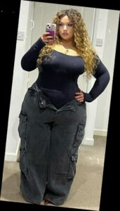 For the baddie girlies, here are some ways to eat up that baddie look 3 A Plus Size woman in Black long sleeve square neck, bodysuit, Black wide leg, cargo jeans, Red heels, Gold necklace