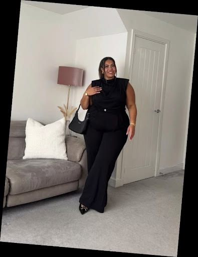 Some Chic Office Outfits for Plus Size Queens, style with class! 4 A plus size woman in Black sleeveless high-neck blouse with padded shoulders Black wide-leg high-waisted trousers Black leather shoulder bag Black pointed-toe heels with silver buckle detail Gold watch and gold hoop earrings