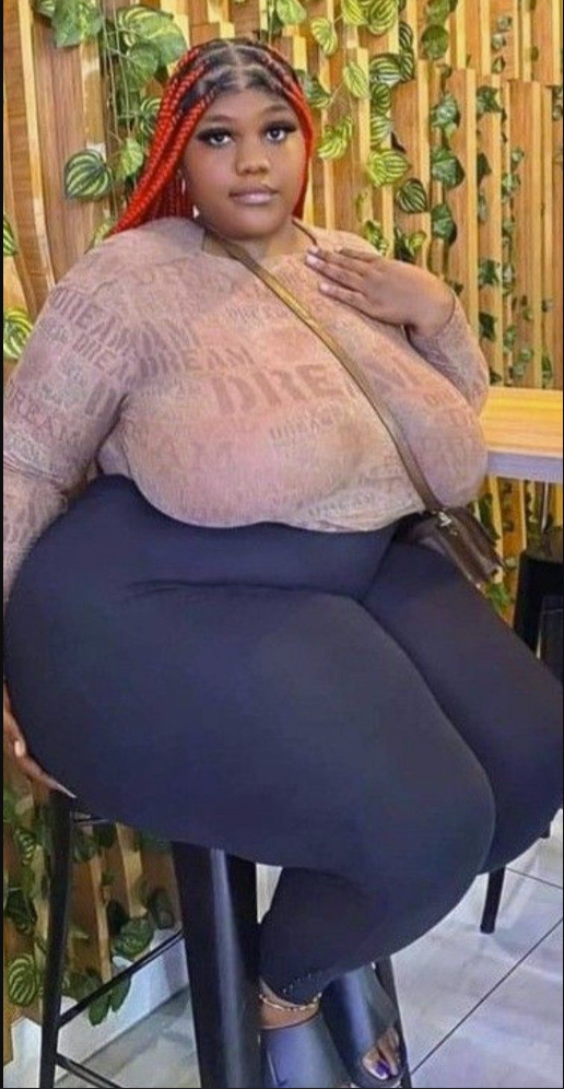 A plus size woman wearing Brown sheer mesh long-sleeve top with alphanumeric graphic text print
High-waisted opaque black leggings
Brown faux-leather crossbody bag with a thin shoulder strap
Black slide platform sandals
Gold chain anklet