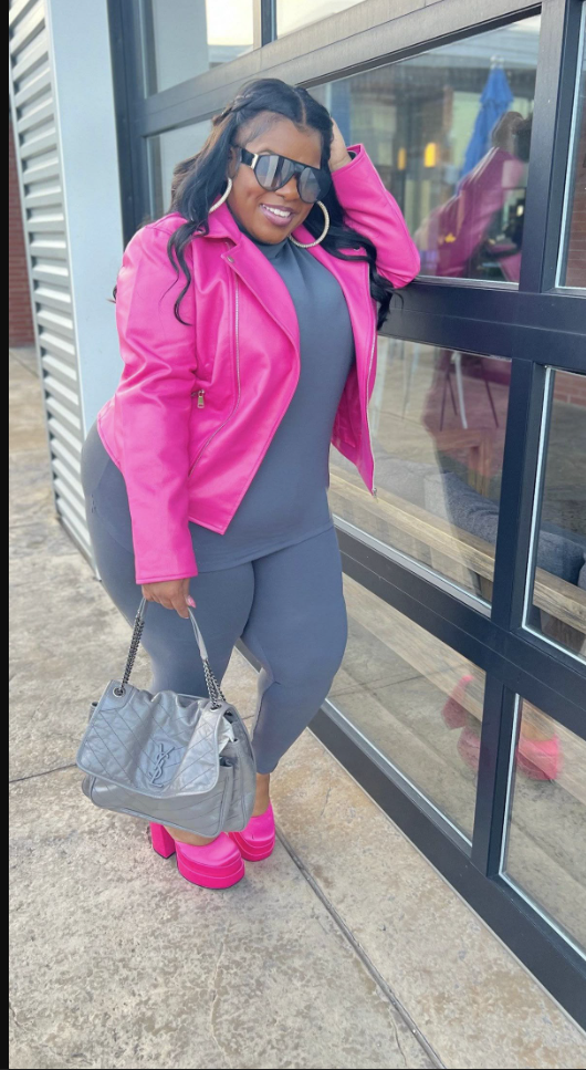 A plus size woman wearing Charcoal gray mock-neck long-sleeve top

Matching charcoal gray high-waisted leggings

Vibrant hot pink faux-leather motorcycle jacket

Hot pink platform block-heel pump shoes

Metallic silver quilted shoulder bag with a chain strap

Large gold hoop earrings

Flat-top black shield sunglasses