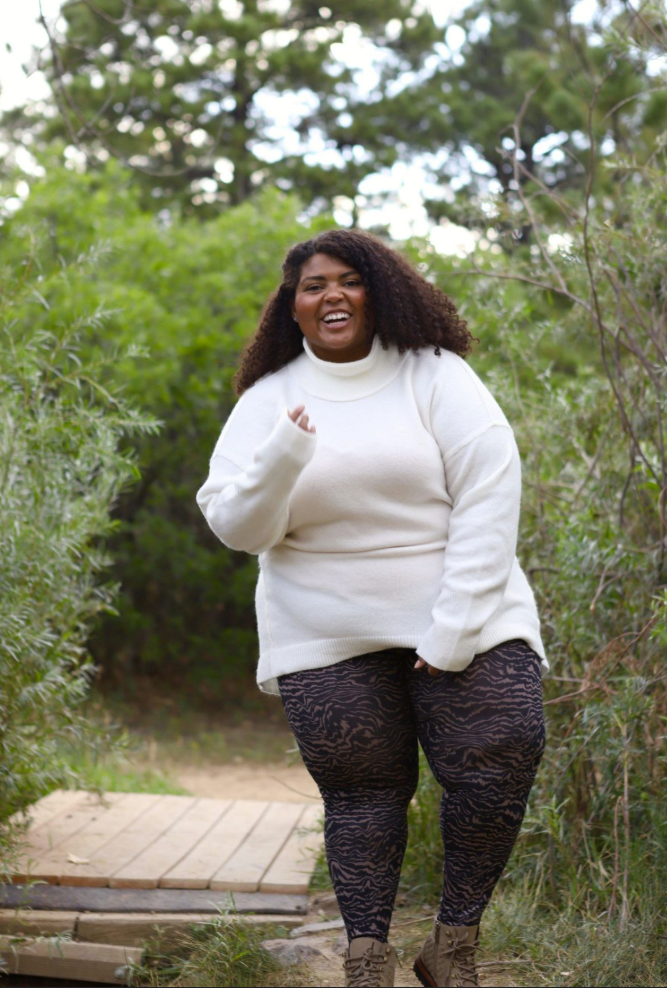 A plus size woman wearing Cream oversized slouchy turtleneck knit sweater with dropped shoulders

Black and brown tiger stripe print high-waisted leggings

Tan lace-up utilitarian hiking boots