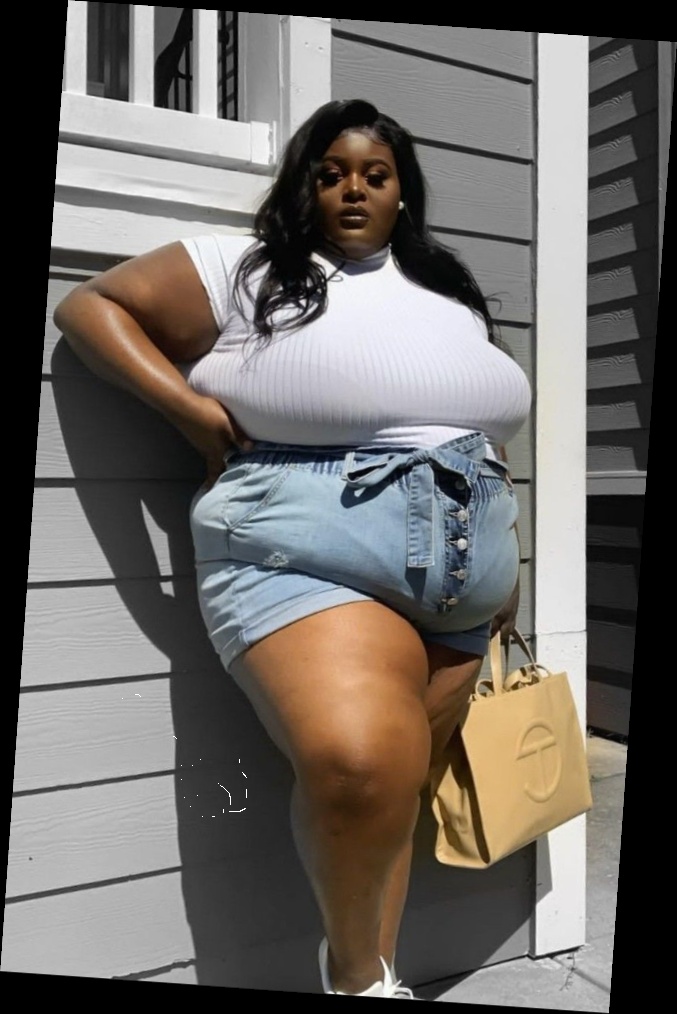 A plus size woman wearing White short sleeve ribbed mock-neck top

High-waist light wash denim shorts with sash tie belt

Beige leather tote bag with logo