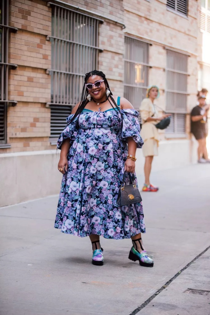 Ideal summer outfit for plus size women 4 A plus size woman wearing Purple and blue floral print off-the-shoulder midi dress Tie-dye platform lug-sole loafers Sheer black ankle socks Small black croc-effect handbag Pink marble-frame sunglasses White floral drop earrings Gold chain bracelet