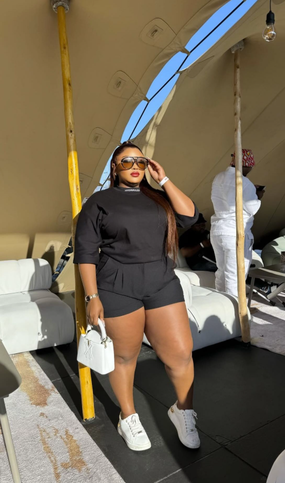 Sun-Ready Summer Vacation Outfits for Plus Size Women 4 A plus size woman wearing Black oversized short-sleeve t-shirt with a mock neck Black tailored high-waisted shorts White leather low-top sneakers White structured mini top-handle bag Tortoiseshell oversized sunglasses Gold chain bracelet Gold watch