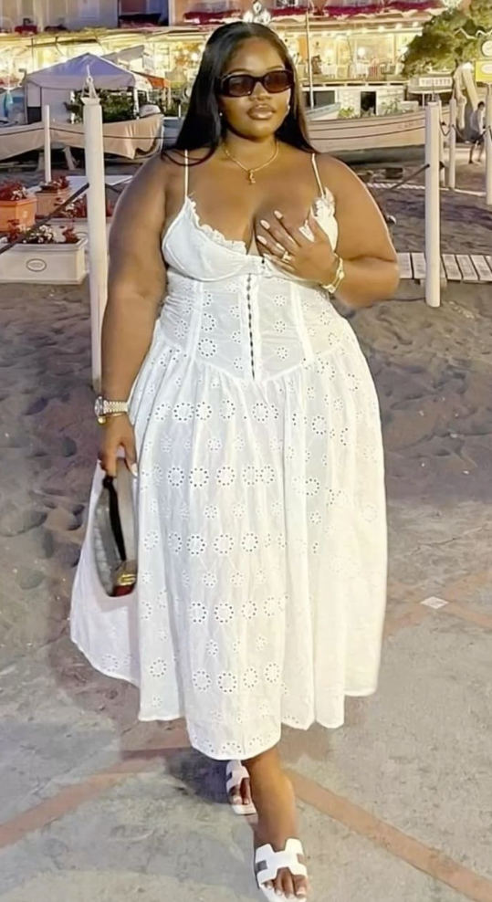 A plus size woman wearing White eyelet lace midi dress with a corset-style bodice and spaghetti straps White leather cutout slide sandals (H-style slides) Dark tint rectangular sunglasses with thick frames Gold pendant necklace Gold chain bracelet Gold luxury watch with a link bracelet Silver and gold metallic statement rings Taupe and white leather shoulder bag with gold hardware