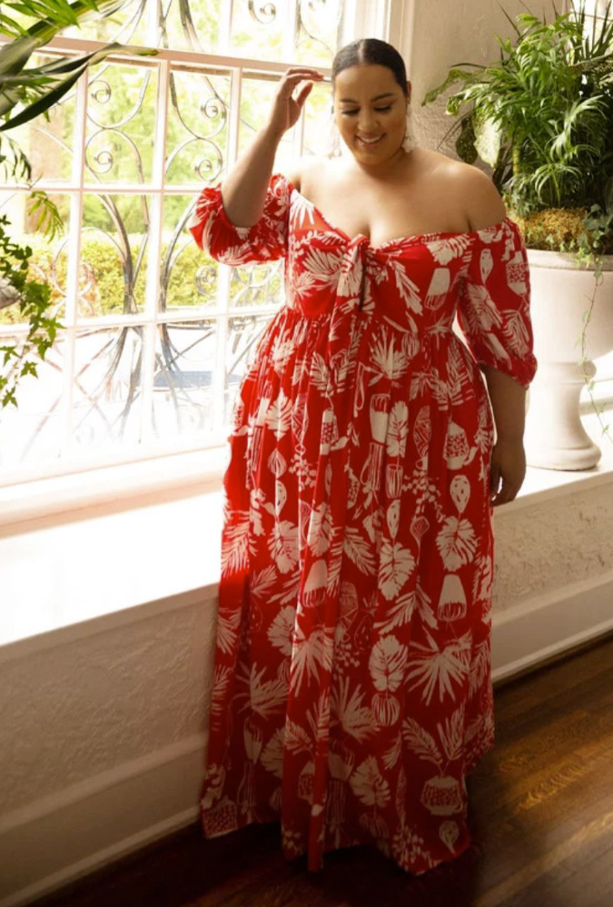 A plus size woman wearing Red and white tropical leaf print off-the-shoulder maxi dress
Tie-front detail at the bust with a subtle cutout accent
Elbow-length puff sleeves with elastic cuffs
White statement tassel drop earrings