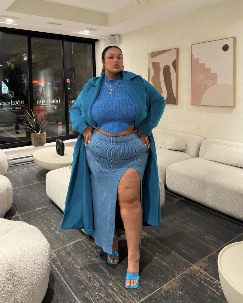 After Dark Glow: Baddie Night Out Outfits for Plus Size Women 3 A plus size woman wearing Teal blue longline trench coat
Royal blue ribbed knit cropped halter sweater top with a pointed hem
Slate blue ribbed knit maxi skirt with a high thigh slit
Blue patent leather square-toe slide heeled sandals
Layered silver chain necklaces