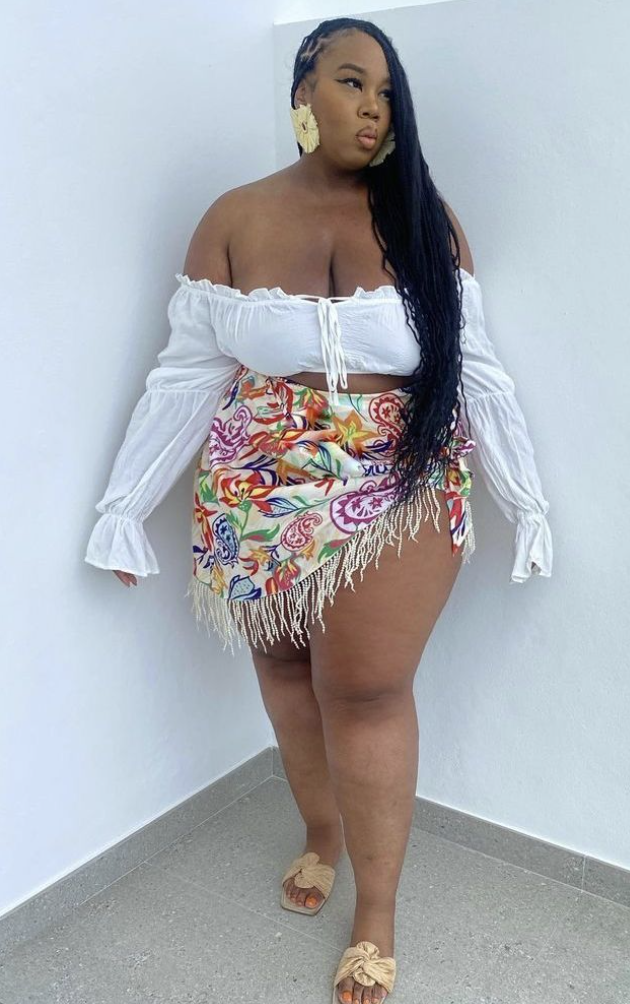 After Dark Glow: Baddie Night Out Outfits for Plus Size Women 6 A plus size woman wearing White off-the-shoulder smocked crop top with flared long sleeves
Multicolor floral paisley print wrap mini skirt with cream fringe trim
Beige woven raffia slide sandals with a knotted bow detail
Oversized cream architectural statement earrings