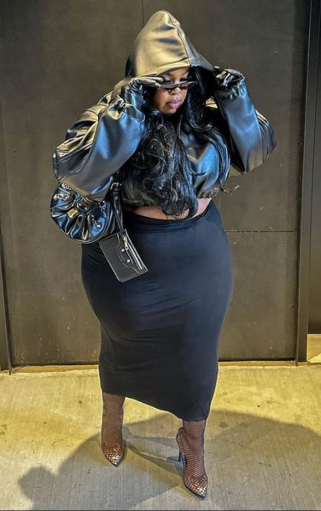 After Dark Glow: Baddie Night Out Outfits for Plus Size Women 7 A plus size woman wearing Black faux-leather cropped hooded puffer jacket
Black faux-leather gloves
Black high-waisted bodycon maxi skirt
Black fishnet pointed-toe stiletto pumps
Black leather motorcycle-style shoulder bag with mirror detail
Slim black rectangular sunglasses