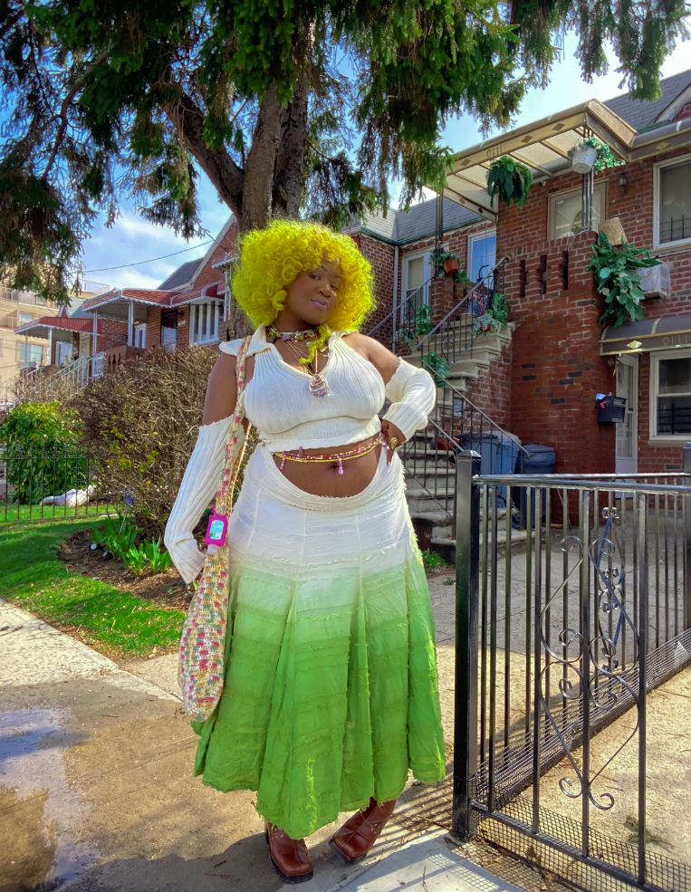 A plus size woman wearing White knit halter top with collar
White knit detached long sleeves
Green ombre tiered ruffle maxi skirt
Layered beaded belly chains
Colorful crochet shoulder bag
Brown leather square-toe boots
Layered beaded necklaces