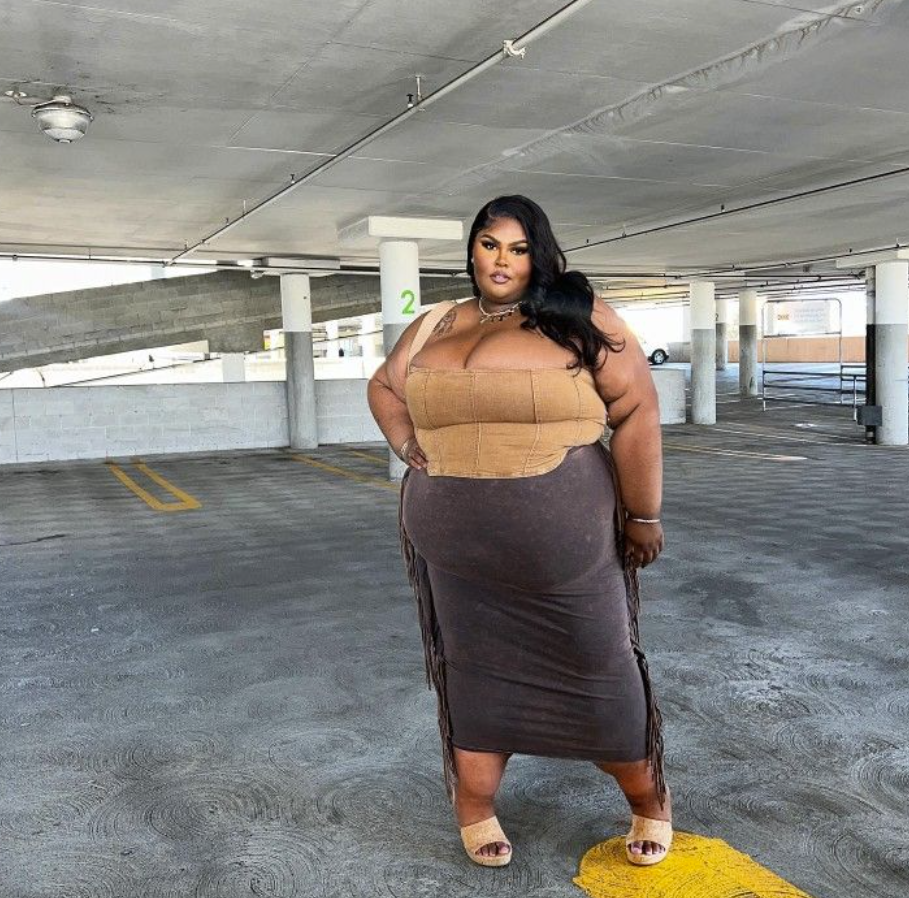 Skirt Season Forever: Flattering Skirt Outfits for Plus Size Women 3 A plus size woman wearing Tan strapless corset-style top
Dark brown midi skirt with fringe details
Beige open-toe heeled sandals
Silver layered necklace
Silver bracelet
Large hoop earrings