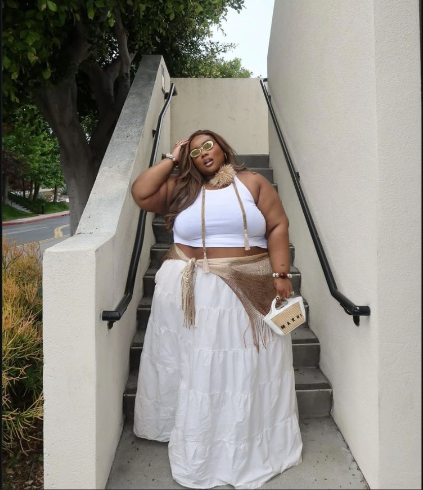 Skirt Season Forever: Flattering Skirt Outfits for Plus Size Women 6 A plus size woman wearing White ribbed crop tank top
Beige fringed shawl/wrap
White tiered maxi skirt
Yellow-tinted sunglasses
Woven handbag with tassels
Gold jewelry (necklaces, bracelets)