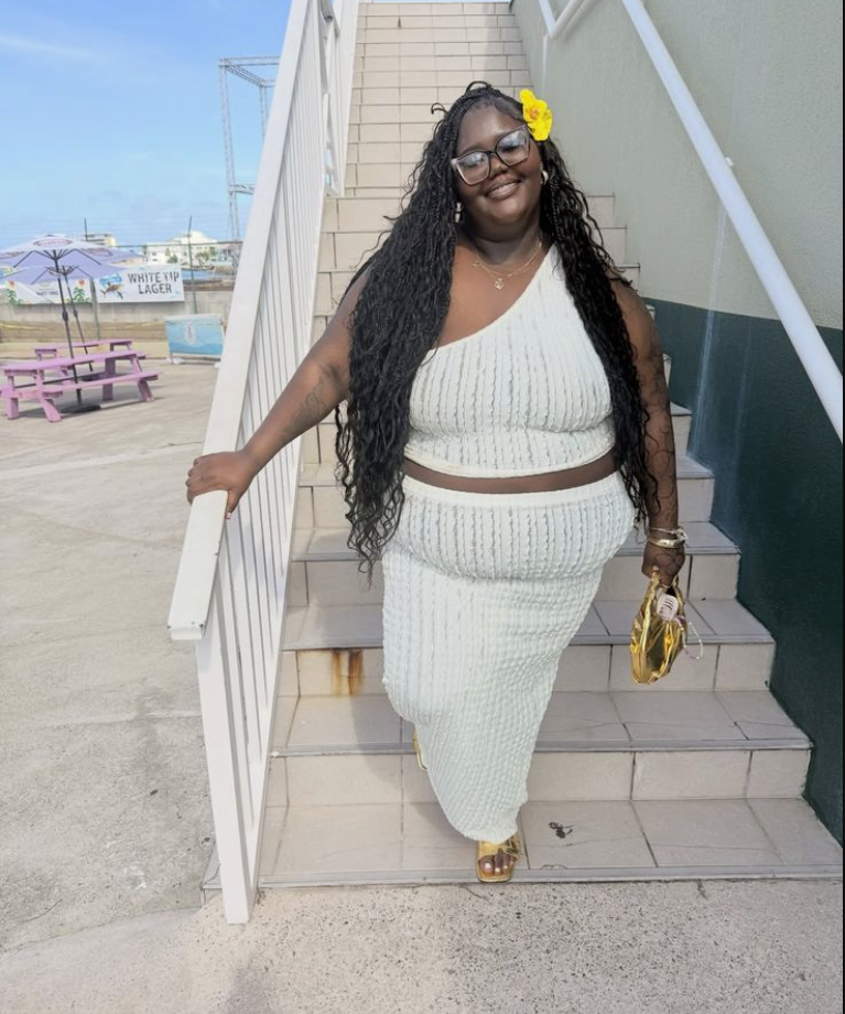 Skirt Season Forever: Flattering Skirt Outfits for Plus Size Women 9 A plus size woman wearing White one-shoulder knitted crop top
White knitted midi skirt
Brown thin belt
Gold clutch bag
Yellow flower hair accessory
Gold jewelry