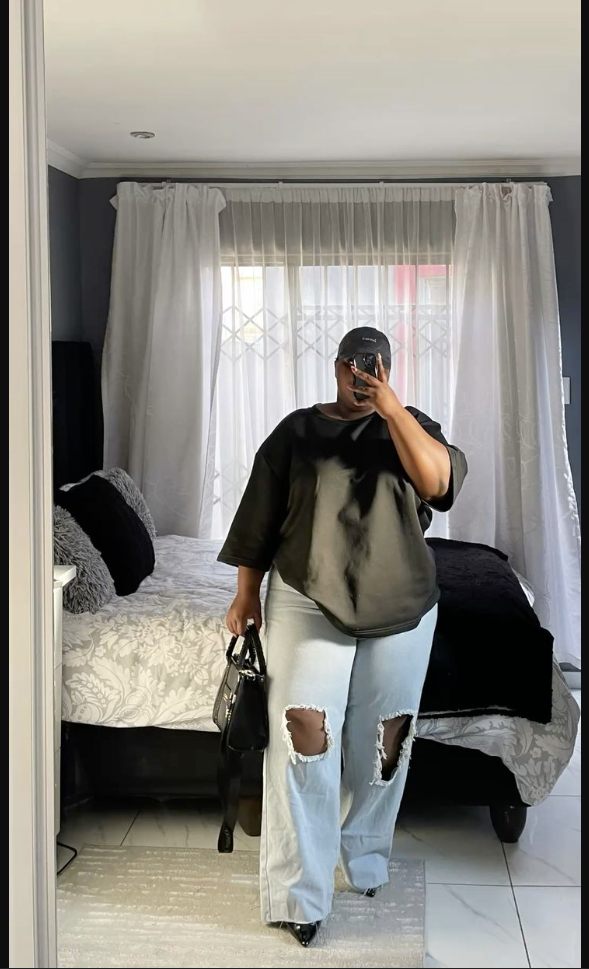 Daytime Charm: Cute & Comfortable Lunch Outfits for Plus Size Women 3 A plus size woman wearing Oversized black short-sleeve t-shirt Light-wash wide-leg ripped jeans Black baseball cap Black pointed-toe heels Black handbag Gold rings