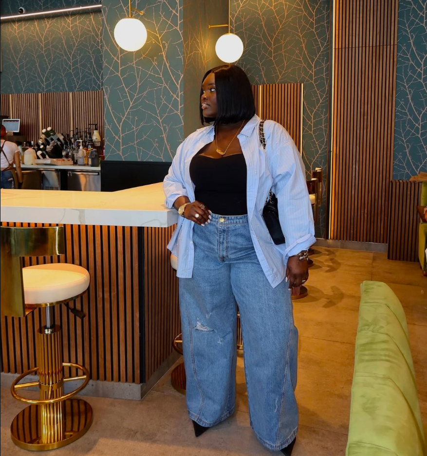 Daytime Charm: Cute & Comfortable Lunch Outfits for Plus Size Women 7 A plus size woman wearing Light blue oversized button-up shirt Black tube top Medium-wash wide-leg ripped jeans Black pointed-toe heels Black chain-strap handbag Gold layered necklaces and bracelets