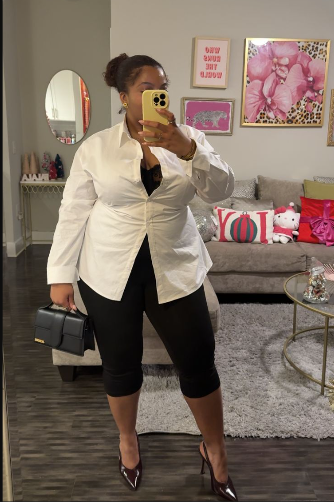 A plus size woman wearing White oversized button-up shirt
Black capri leggings
Black lace bralette underneath
Burgundy pointed-toe heels
Black structured handbag
Gold jewelry