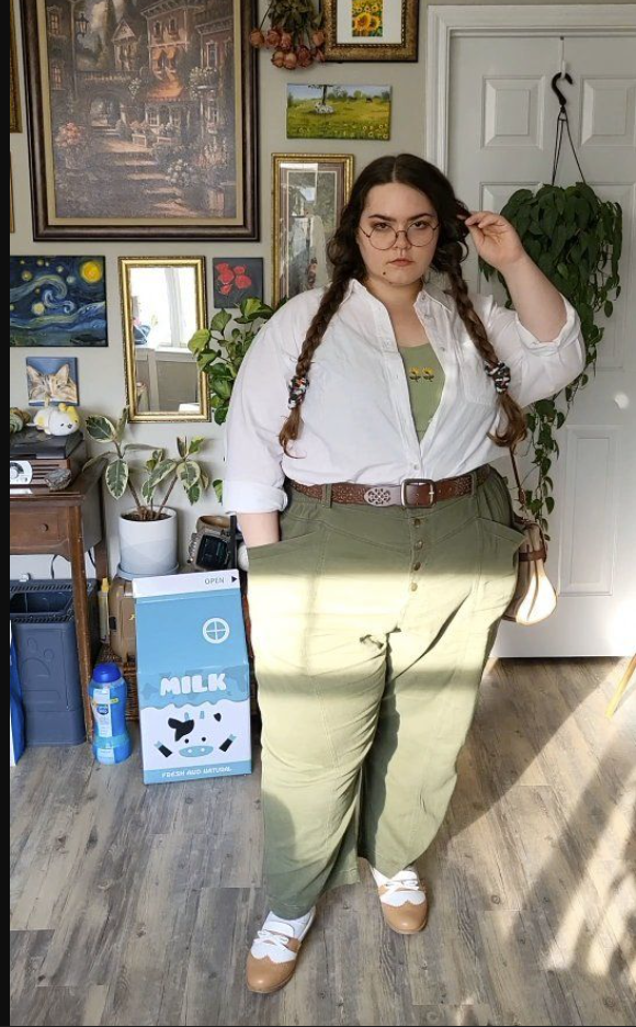 A plus size woman wearing White button-up shirt Sage green camisole Olive green cargo pants Brown leather belt with silver buckle Two-tone Mary Jane shoes Woven crossbody bag