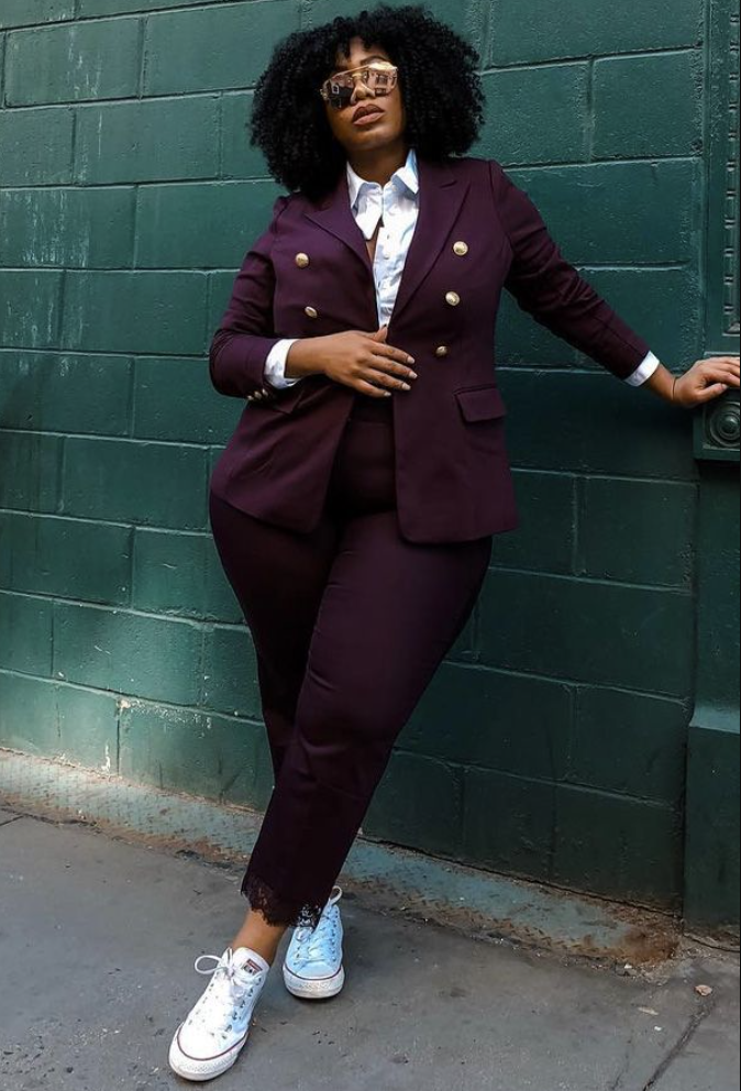 A plus size woman wearing Burgundy double breasted blazer
Burgundy pants
White collared button up shirt
Light blue lace-up sneakers