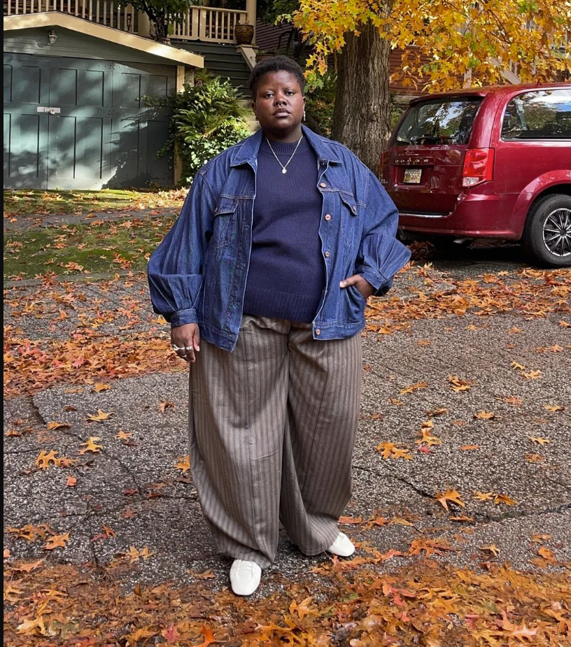 A plus size woman wearing Blue denim jacket
Navy blue sweater
Beige striped wide leg pants
White sneakers