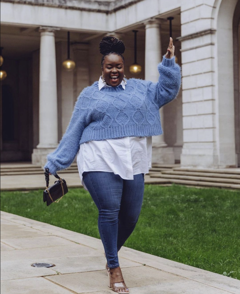 A plus size woman wearing Blue fuzzy knit cropped sweater
White button-up shirt
Dark blue skinny jeans
Nude strappy heels
Black chain-handle handbag