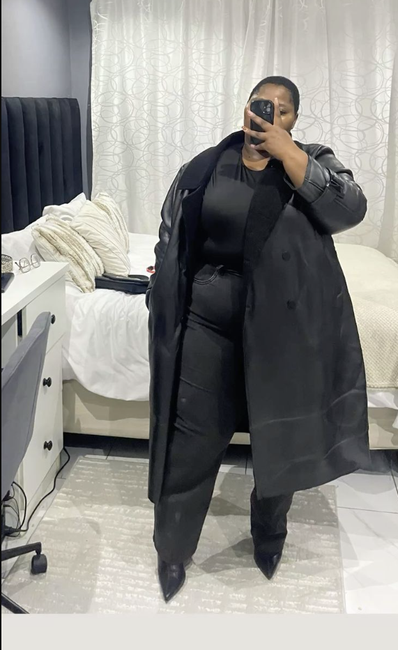 A plus size woman wearing Black long double-breasted trench coat
Black bodysuit
Black cargo-style wide-leg pants
Black pointed-toe ankle boots