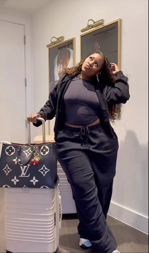 A plus size woman wearing Dark grey cropped long-sleeve top
Dark grey zip-up hoodie
Dark grey drawstring sweatpants
Black and white Louis Vuitton tote bag
White sneakers