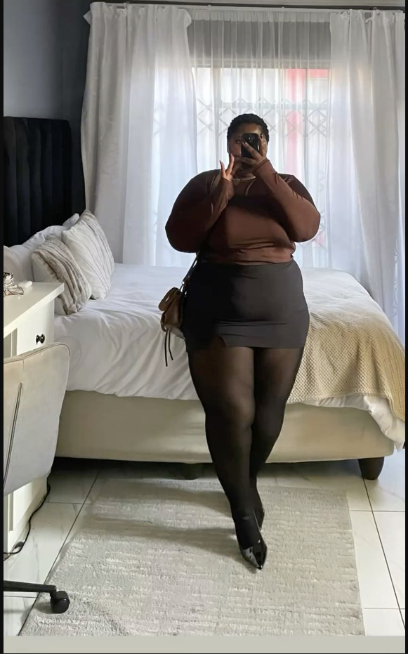A plus size woman wearing Brown long sleeve top Black mini skirt Black opaque tights Black pointed toe heels Brown crossbody bag