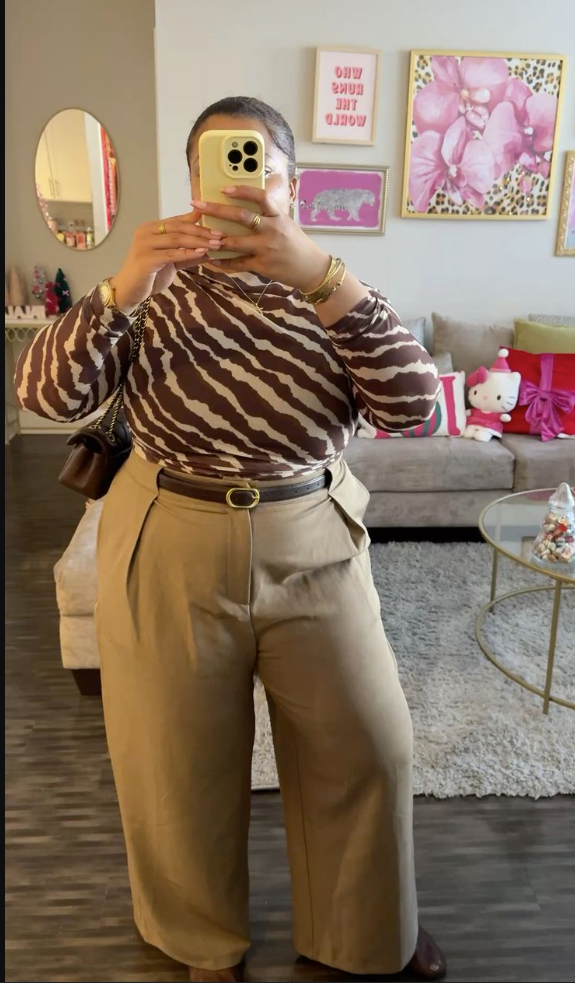 A plus size woman wearing Brown and white zebra print top
Beige high waisted trousers
Black belt with gold buckle
Brown shoes
Brown crossbody bag