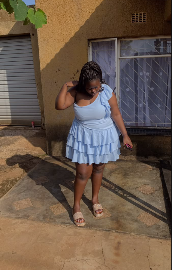 A plus size woman wearing Light blue one-shoulder ruffled top Light blue tiered ruffle mini skirt Sparkly beige platform slides