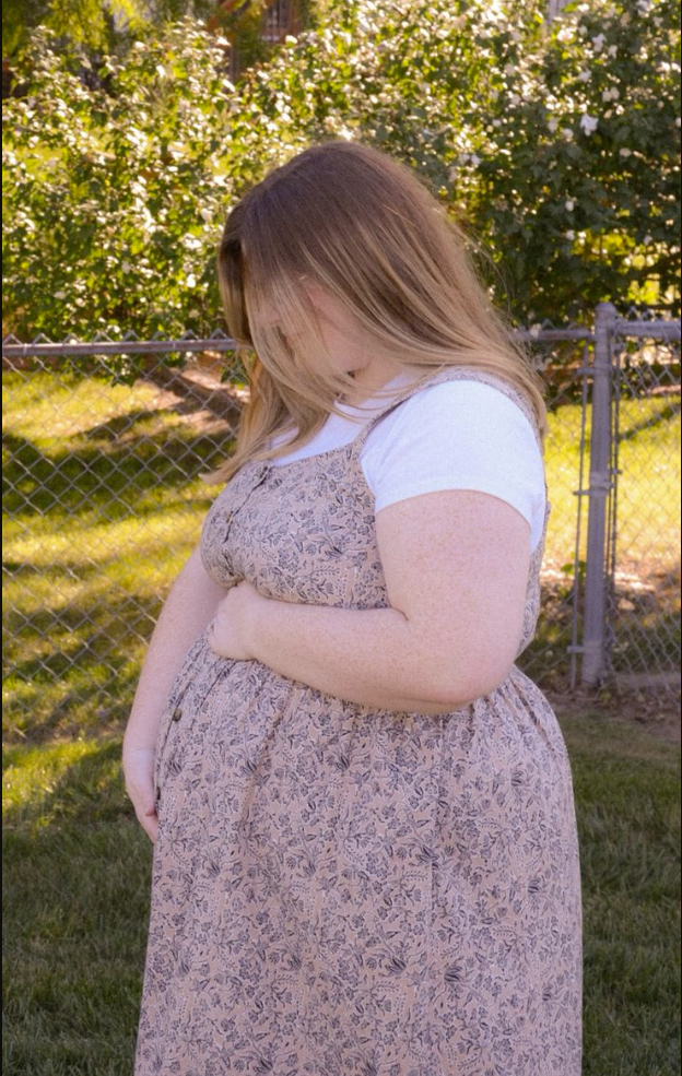A plus size woman wearing Floral print button-front jumper dress White short sleeve t-shirt underneath